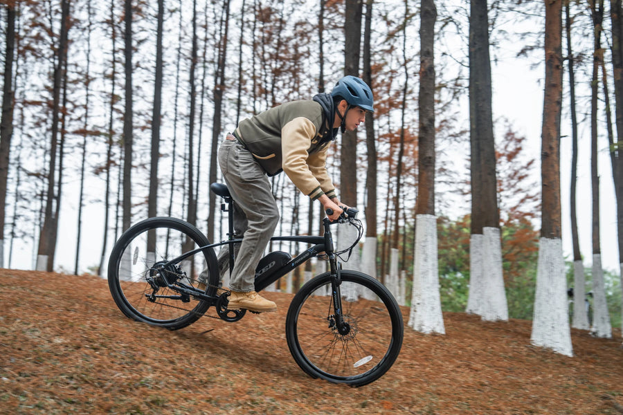 A helmeted rider on a TXED Trail on a leaf-covered slope among trees.
